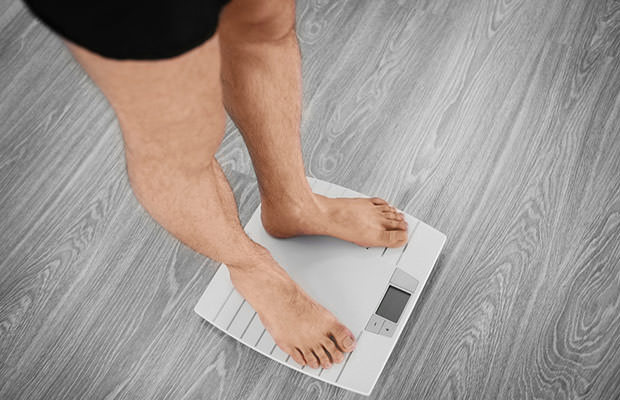 bigstock-Man-standing-on-weight-scale-144563333